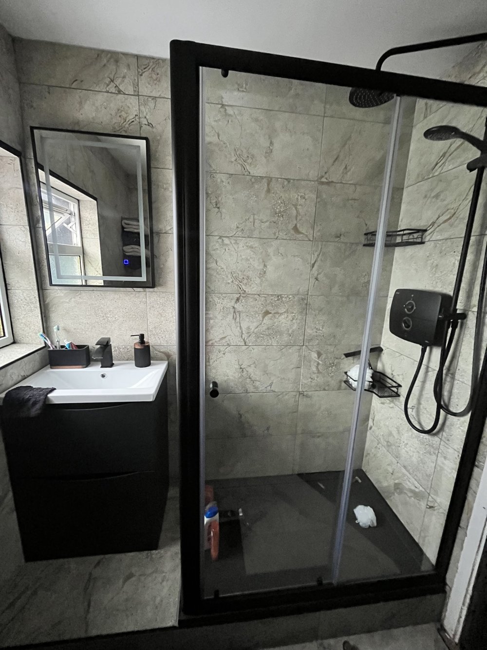 Renovated shower room with a black framed shower enclosure, marble-effect tiles and a black vanity unit
